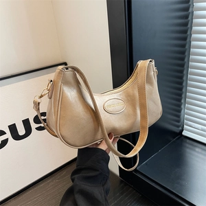 Minimalist beige moon-shaped shoulder bag with textured leather and metal detail