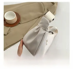 Detail view of white half-moon crossbody bag featuring a cute brown bear cartoon patch