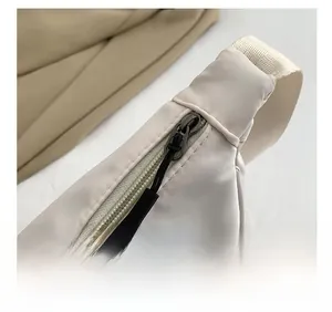 Detailed close-up of smooth black zipper and durable nylon fabric on off-white sling bag