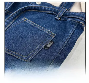 Detailed macro view of dark blue denim tote bag with gold contrast stitching and square pocket