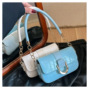 Detail von Taschen mit Krokoprägung in Blau und Weiß mit goldenen U-förmigen Schnallen