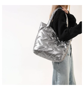 Détail du grand sac cabas matelassé argent métallisé avec bandoulière large sur modèle