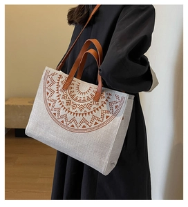 Detail view of large canvas tote bag featuring brown geometric patterns and leather handles