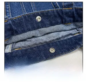 Detailed close-up of metal snap closure and yellow stitching on blue denim tote bag