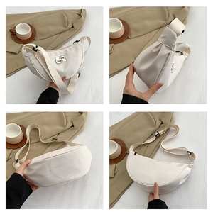 Detail view of the white crescent bag with wide adjustable shoulder strap and zip closure