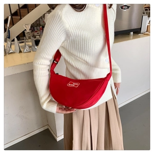 Detail of red nylon crescent crossbody bag with white YUN QING logo worn by a model