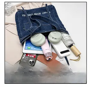 Detail view of denim tote bag showing its large capacity with tablet and daily items