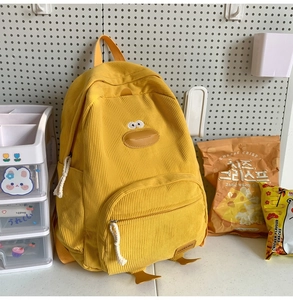 Detail showing soft yellow corduroy fabric and cute 3D duck character design on backpack