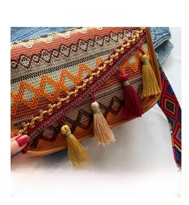 Detail showing jacquard fabric texture and tassel charms on ethnic style crossbody bag