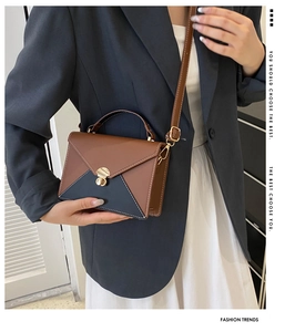 Détail du sac enveloppe bicolore en cuir avec fermoir doré et coutures de précision