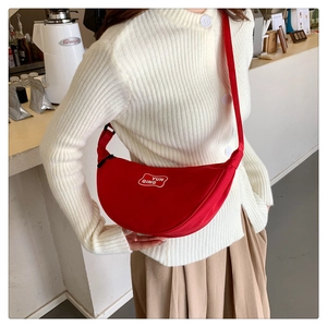 Detail view of the vibrant red crescent bag with white logo on casual fabric
