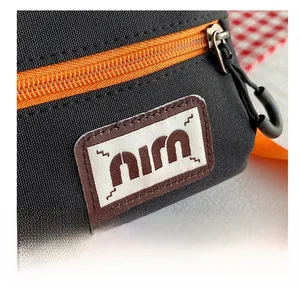 Detailed macro shot of durable black canvas fabric with orange contrast zipper and woven label