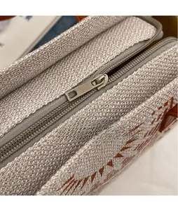 Close-up of smooth silver hardware zipper on textured linen tote bag with geometric patterns