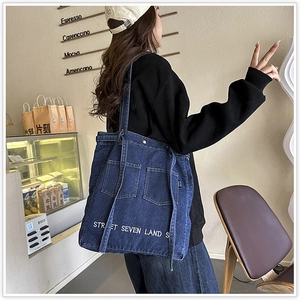 Deep blue denim tote bag with street embroidery shown in a cozy coffee shop scene