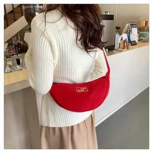 Detailed view of red canvas crescent bag with YUN QING logo worn over the shoulder