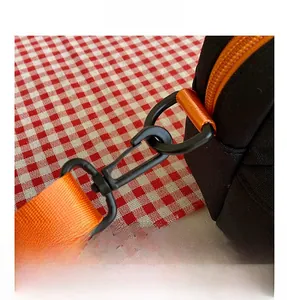 Detail of black canvas bag with orange nylon strap and swivel snap hook closure