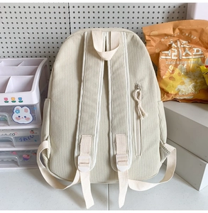 Detail of off-white corduroy backpack showing ribbed texture and side zipper pocket