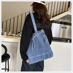 Blue denim tote bag with street style embroidery shown on model in coffee shop setting