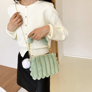Detail of light green faux fur handbag with striped texture and gold chain strap