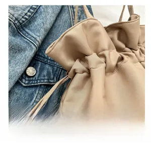 Detail of khaki drawstring tote bag with smooth fabric and neat stitching on denim jacket