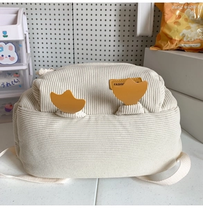 Detail of white corduroy mini backpack with yellow cartoon duck feet and fashion leather label