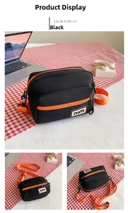 Close-up of black nylon crossbody bag featuring contrast orange zippers and inner compartments