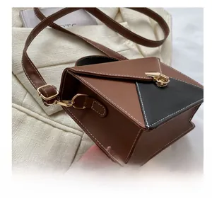 Détails du sac bandoulière bicolore avec coutures contrastées et fermoir rotatif doré