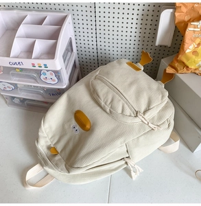 Detailed view of cream corduroy cartoon duck backpack with textured fabric and yellow bill