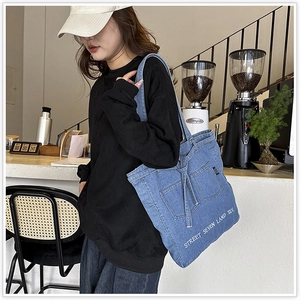 Close-up of the stylish denim tote bag with street embroidery and casual strap details