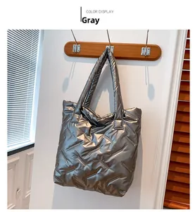 Détail d'un sac cabas gris métallisé matelassé accroché sur un mur dans un intérieur