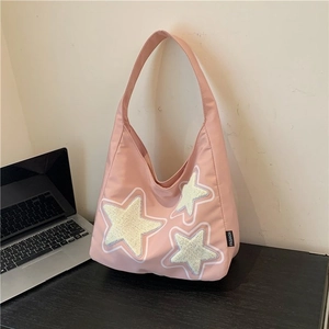 Pink hobo shoulder bag with plush star patches and fashion label on black desk