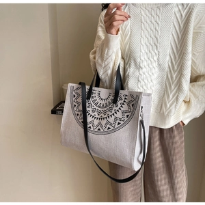 Detail of canvas tote bag featuring ethnic mandala print and black leather handles