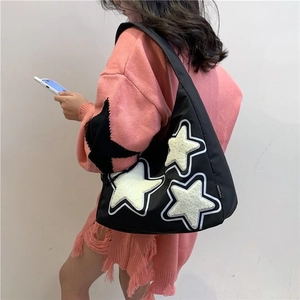 Detail view of black canvas tote bag featuring plush white stars and fashion tag