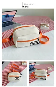 Detailed close-up of a white canvas crossbody bag featuring orange zippers and straps