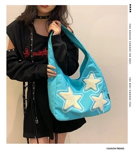 Detail of light blue hobo bag showing plush white star patches and wide shoulder strap