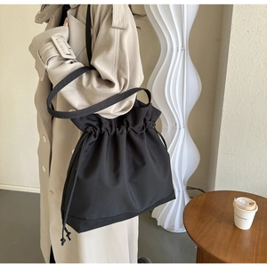 Detail of black nylon drawstring bucket bag showing large capacity and soft fabric texture
