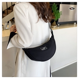 Close-up of black crescent shoulder bag featuring YUN QING logo and wide strap detail