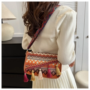 Detail of bohemian knitted crossbody bag with colorful tassels and ethnic shoulder strap