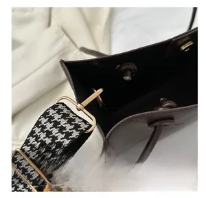 Détail d'un sac à main en cuir marron avec bandoulière pied-de-poule et boucles dorées