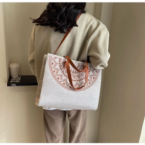 Detail view of ethnic canvas tote bag with brown mandala pattern shown on model back