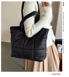 Detailed close-up of black quilted puffer tote bag with thick padded handles