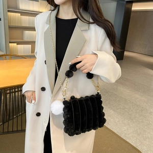 Chic black plush faux fur handbag with gold chain strap and stylish white pompom charm