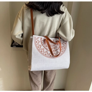 Detailed back view of a beige linen tote bag with brown geometric print and leather straps