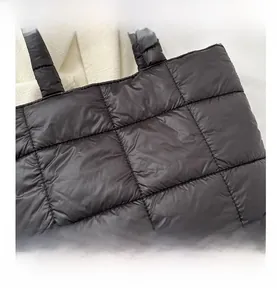 Detailed view of the fine quilted stitching and soft nylon texture on this black tote bag