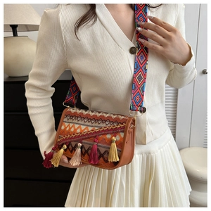 Close-up of bohemian crossbody bag with colorful jacquard strap and multicolor tassels