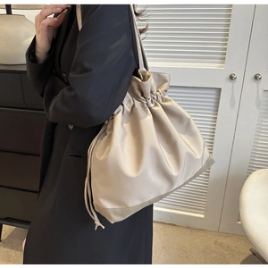 Chic beige drawstring shoulder bag shown in a lifestyle scene with a spacious silhouette