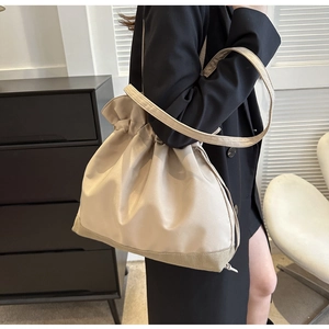 Detail view of beige drawstring shoulder bag showing smooth texture and strap