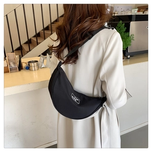 Detail view of black crescent crossbody bag with white YUN QING logo and wide strap