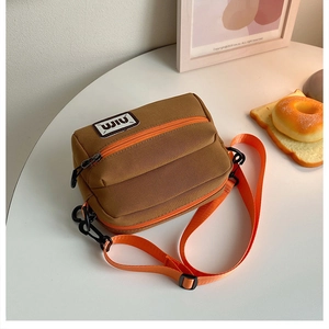 Detailed macro of brown canvas crossbody bag with orange zipper and durable strap