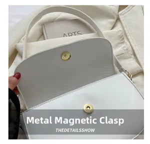 Détail du sac à bandoulière blanc avec fermoir magnétique doré et coutures premium